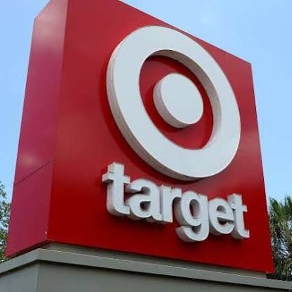Red and white sign with Target logo and text, trees visible in background.