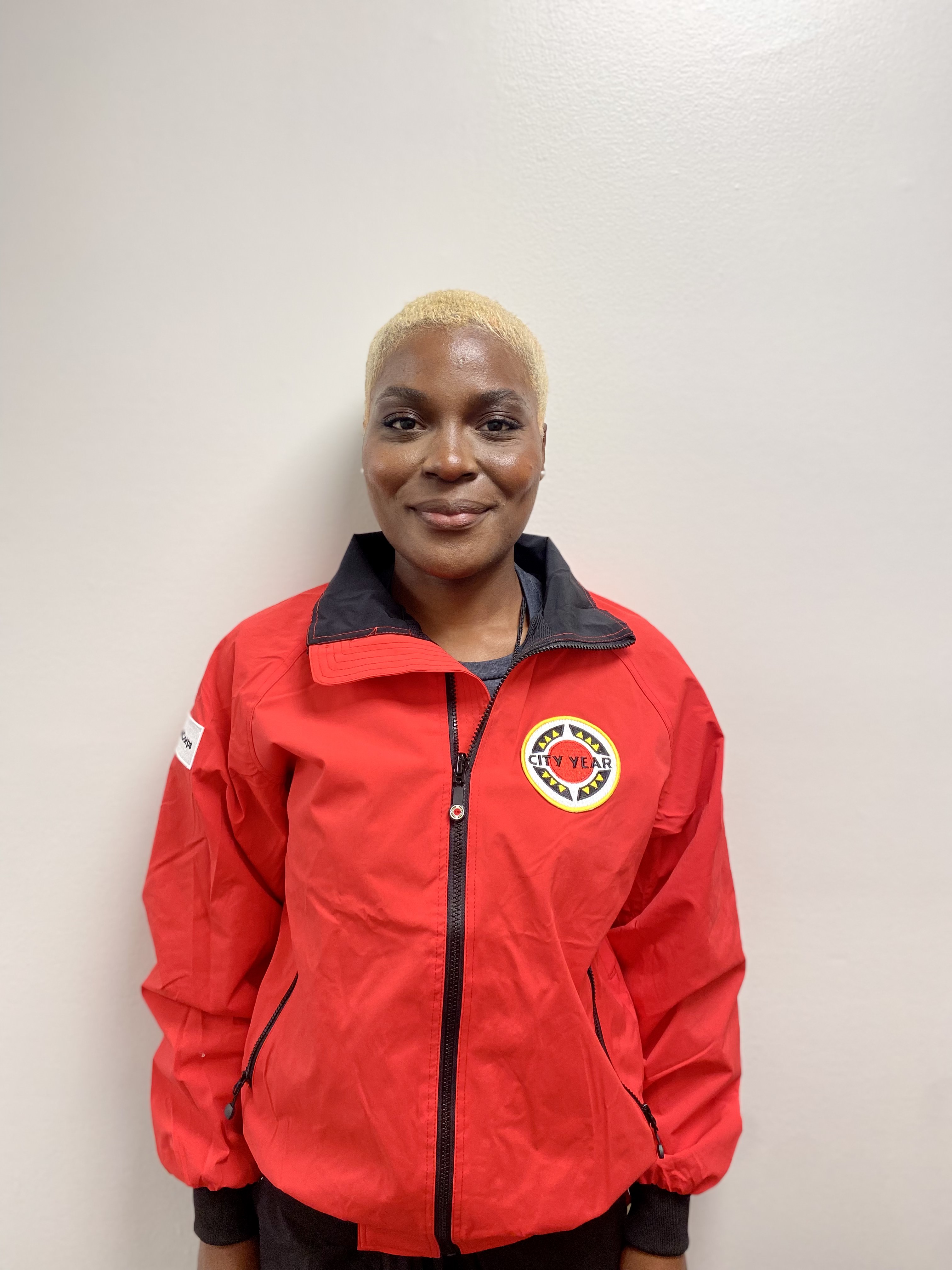 Dark-skinned woman with blond hair wearing red City Year jacket