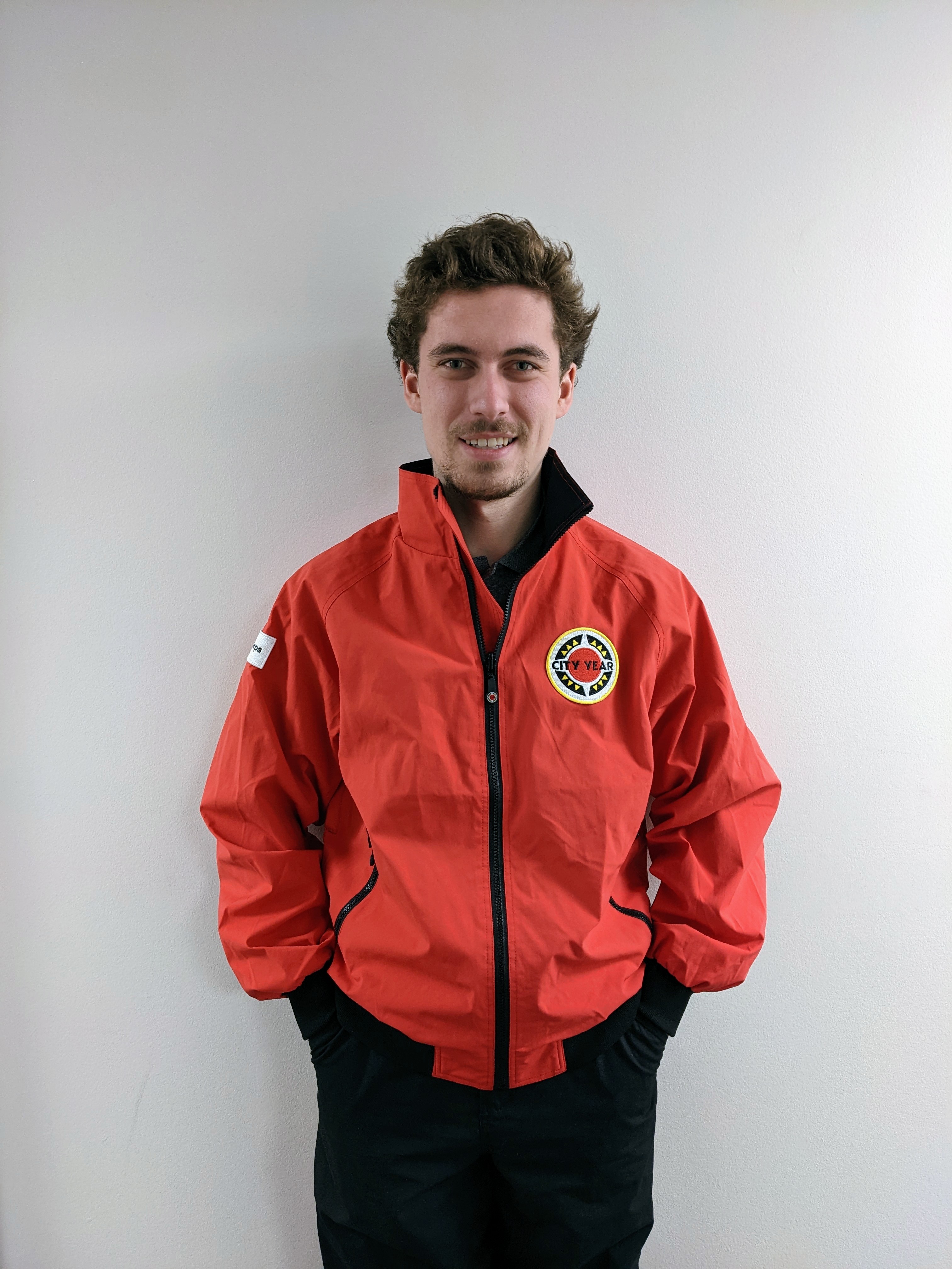Light-skinned man with brown hair wearing red City Year jacket