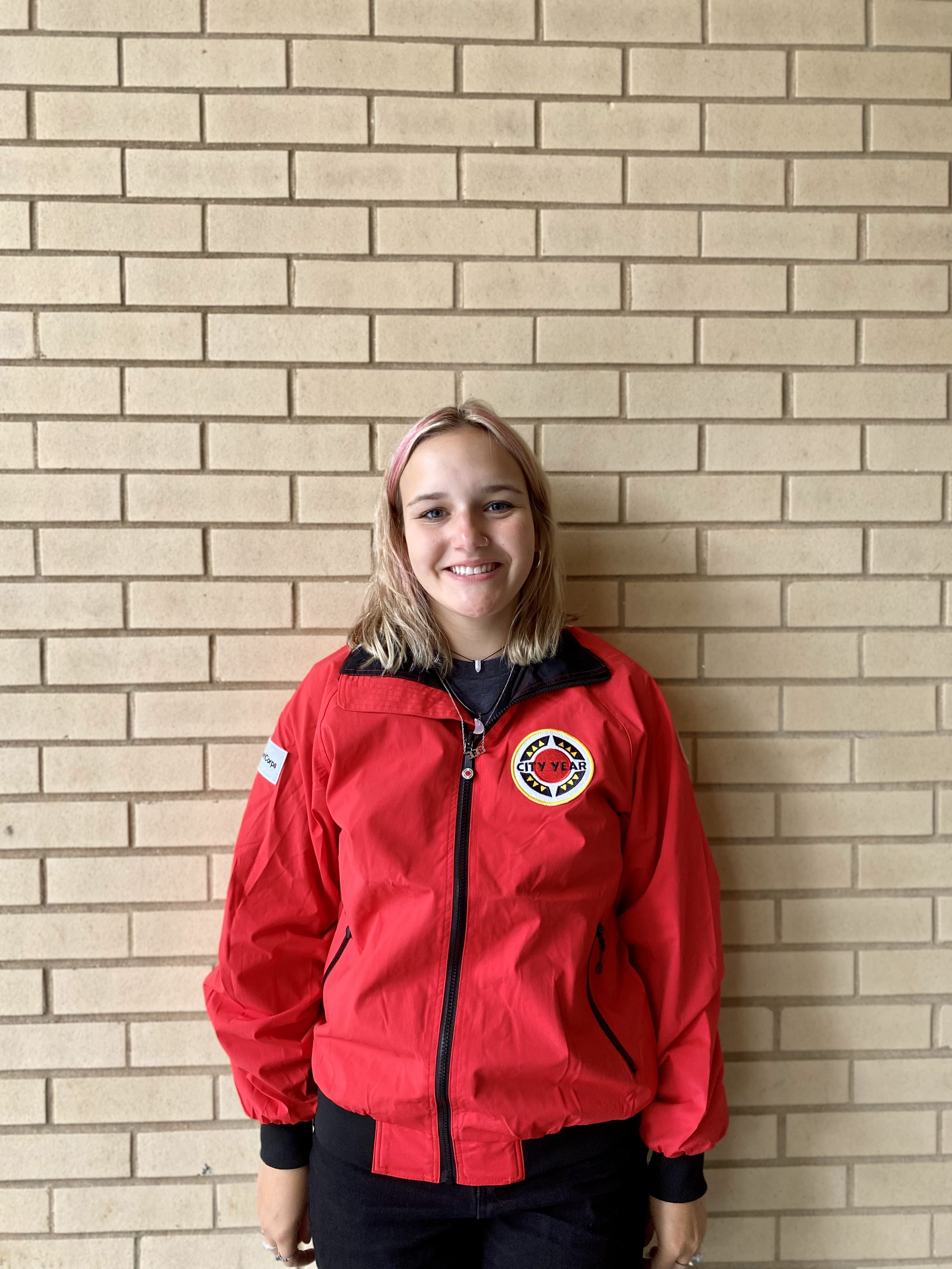 Light-skinned woman with blond hair wearing red City Year jacket