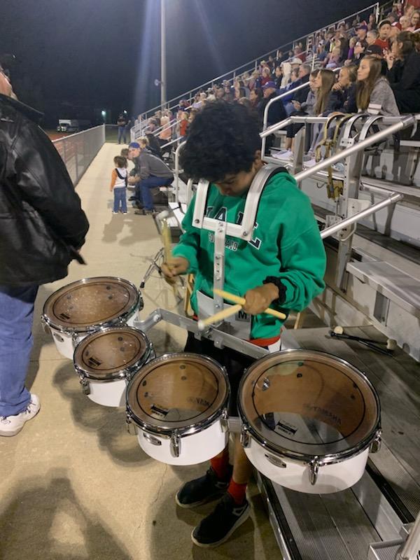 A school playing a set of drums in the football field.