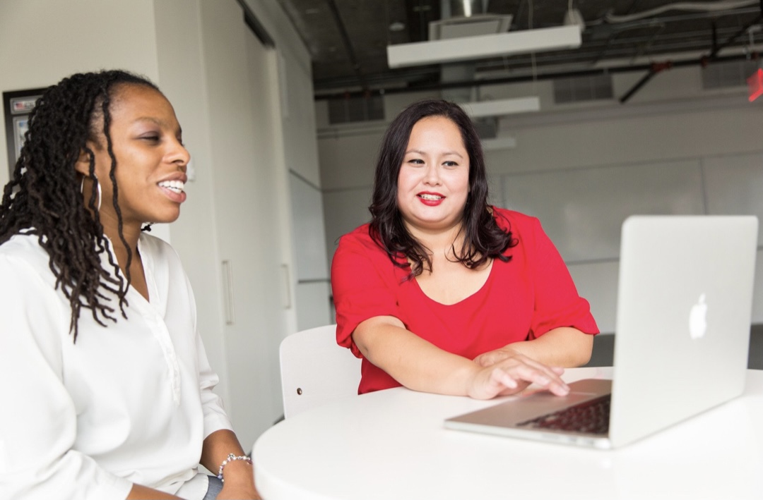 Two people sitting at a computer and smiling