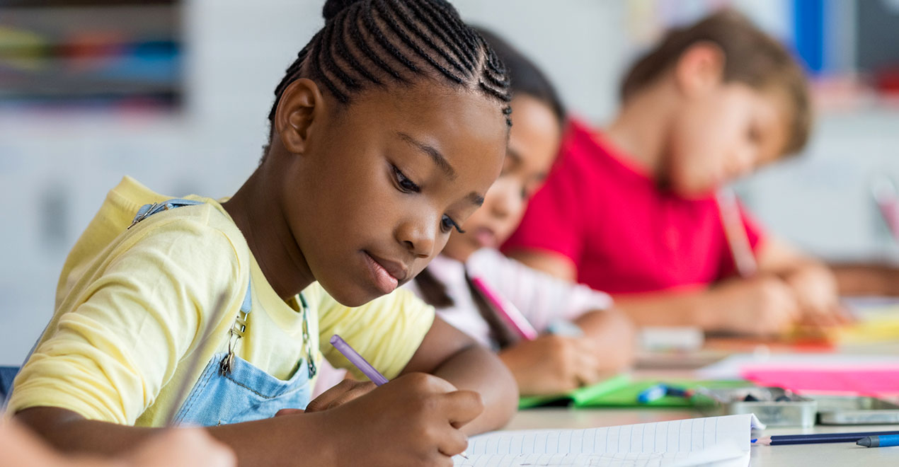 3 young students writing at school desks