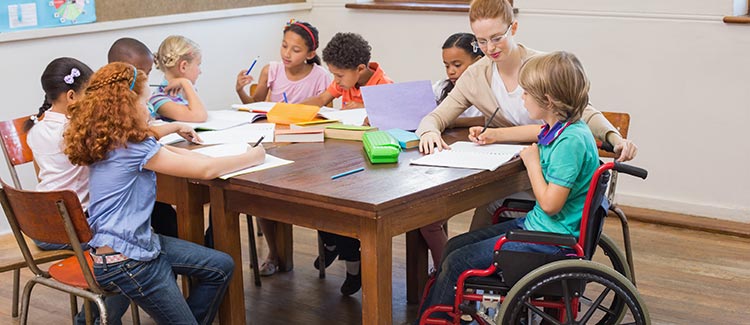 8 students sitting at a table 1 in a wheelchair plus one teacher