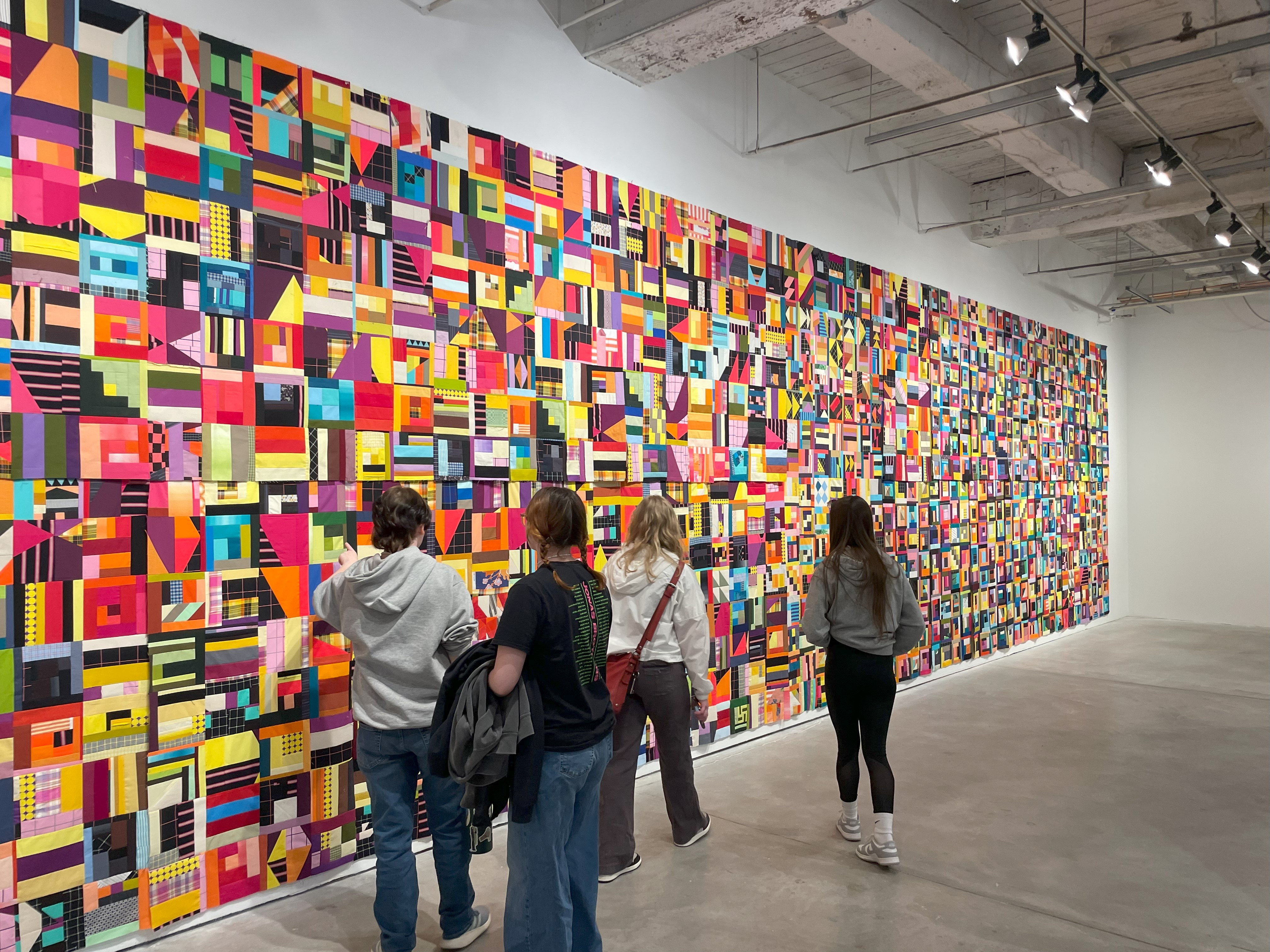 art club students observe a wall of art, rectangles of multiple colors put together