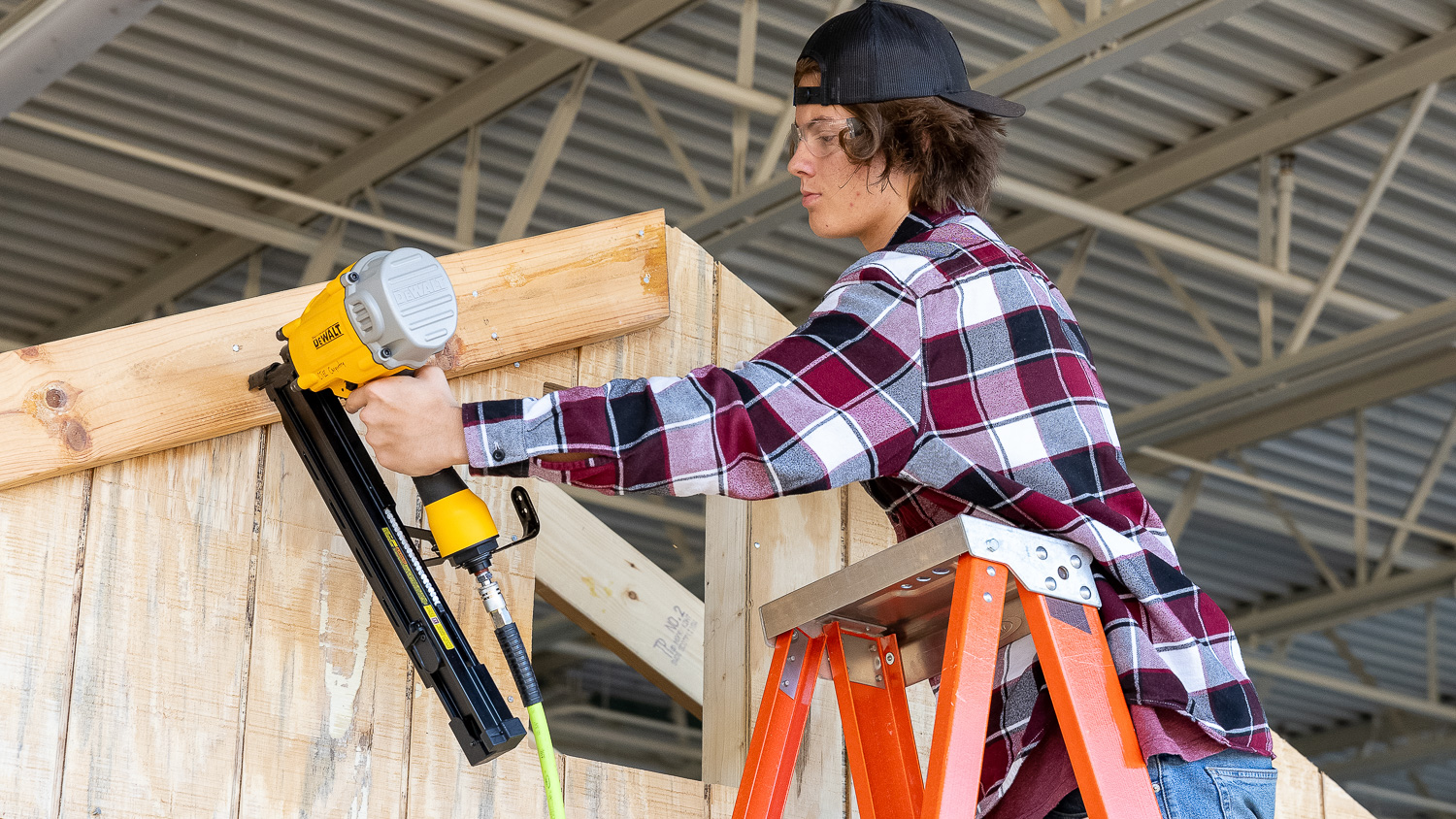 Carpentry student on a l;adder using a nail gun to install joists.