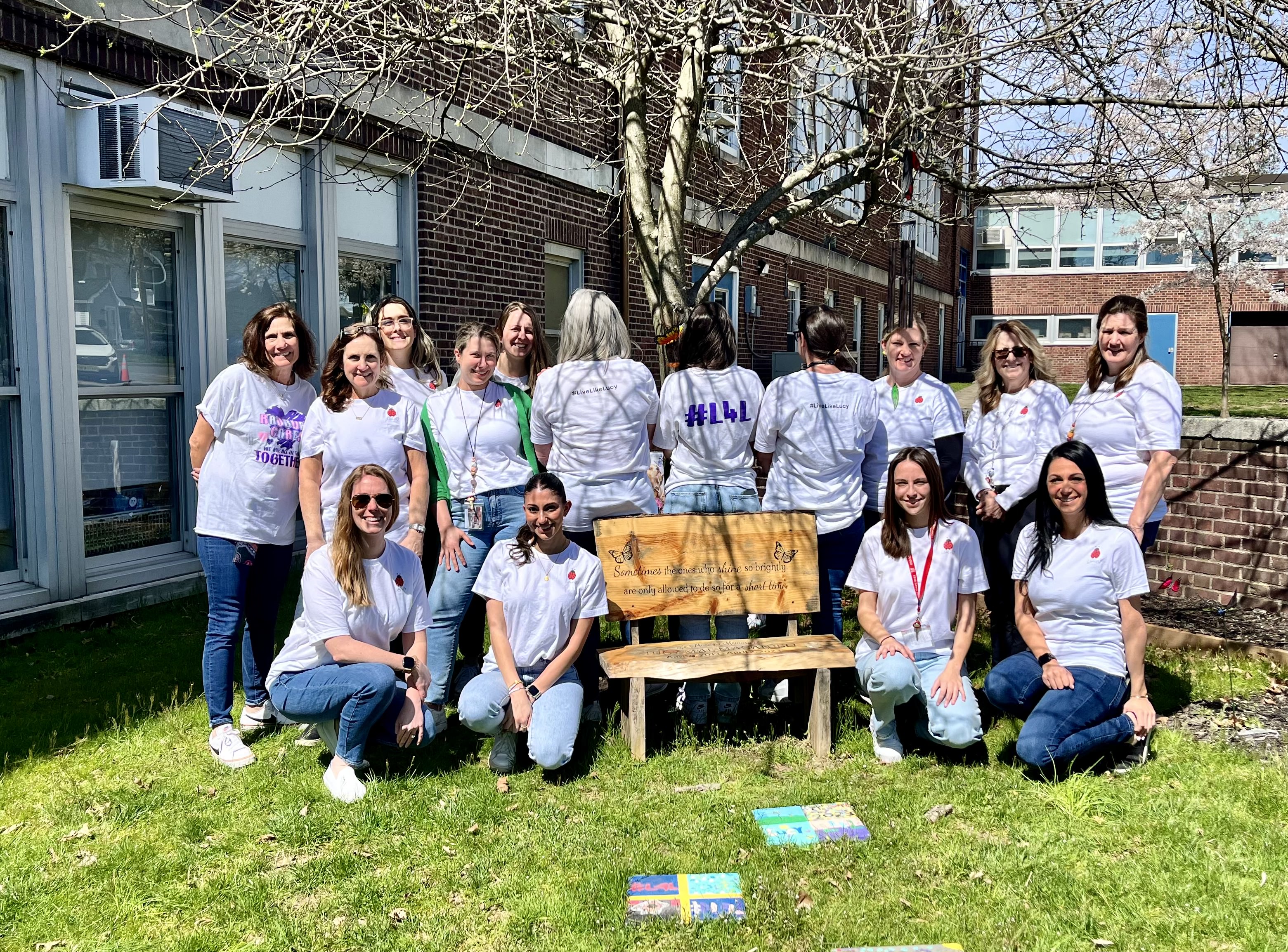 Staff standing in butterfly garden posing with white "Lucy" shirts