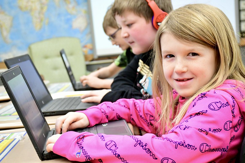 Student smiling while working on a laptop