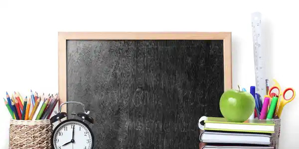 Chalkboard with an apple, clock, textbooks and alarm clock