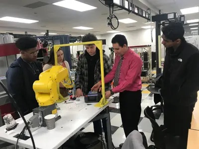 Students huddled a manufacturing table