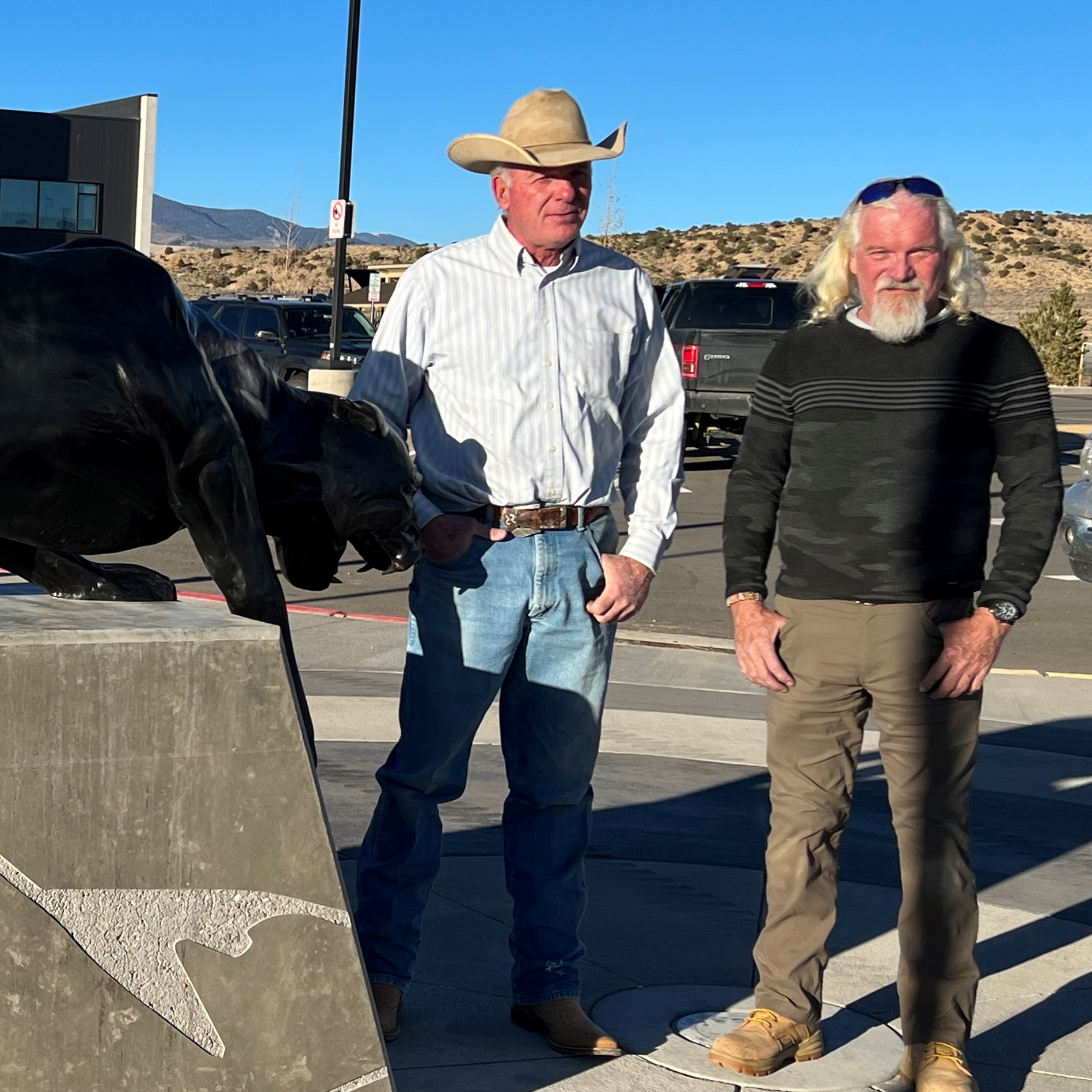 Two men standing next to scupltor