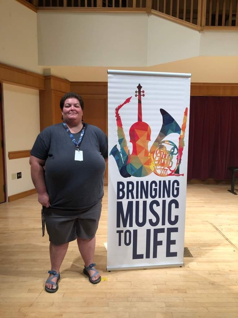 Music teacher standing next to a music sign