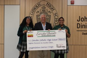 2 students and staff holding big check