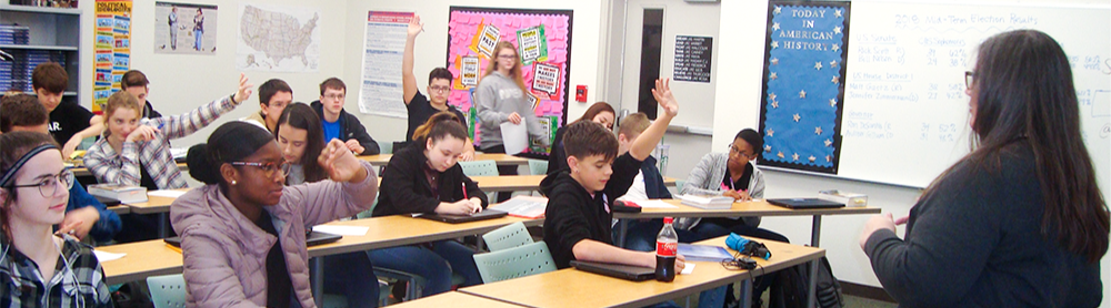 Students sitting at classroom raising their hand