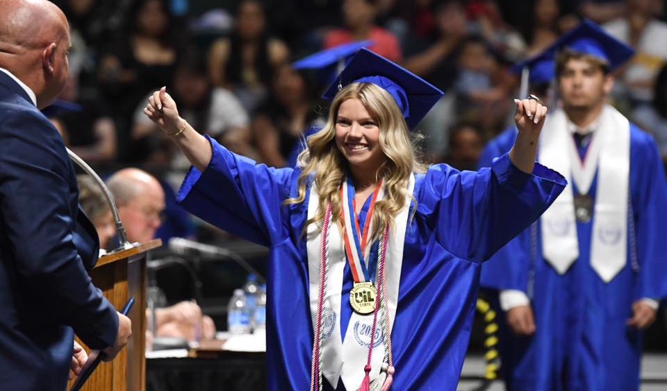 Student celebrates while walking across the stage at graduation 
