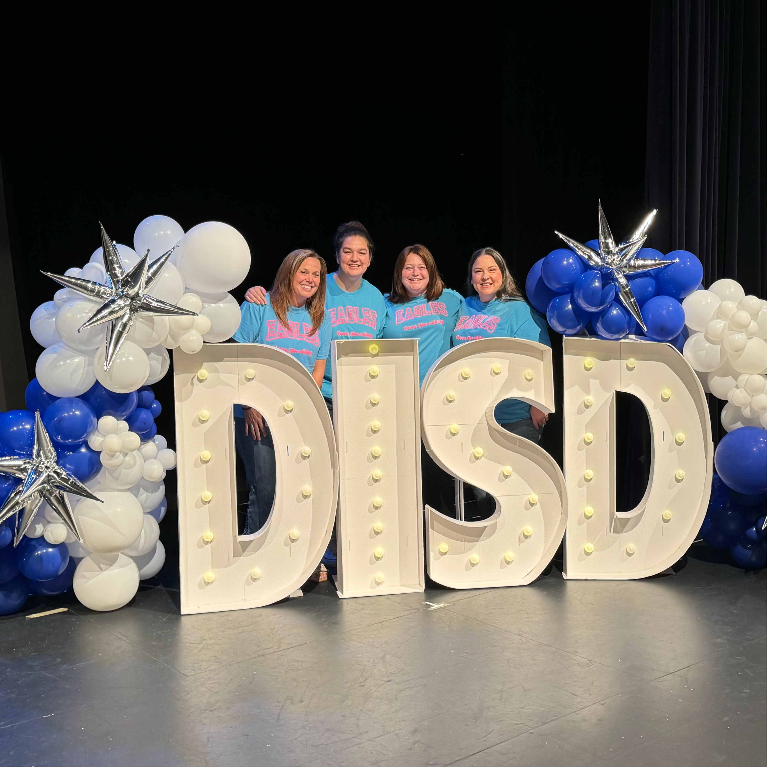 rotation teachers behind big DISD letters and balloons