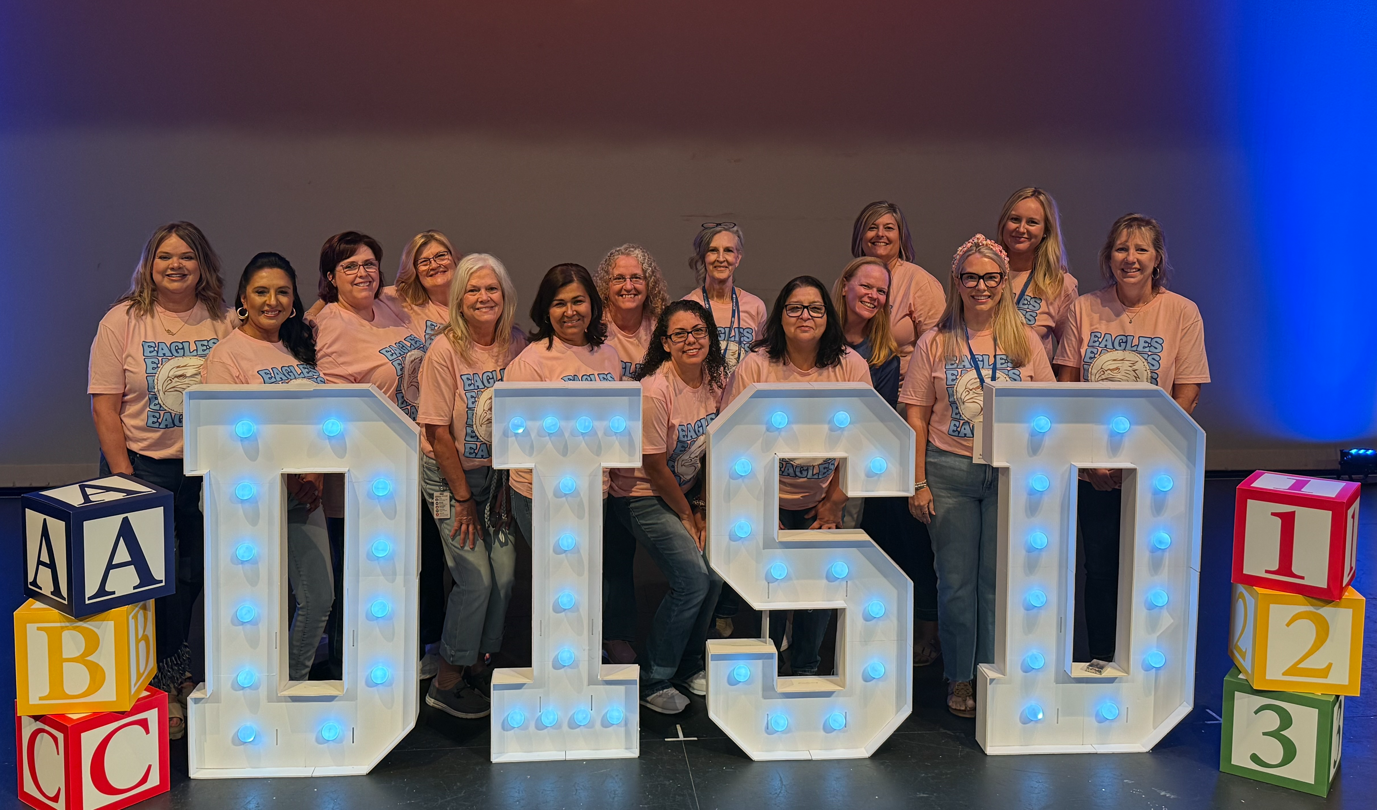 Teachers standing behind big letters DISD.