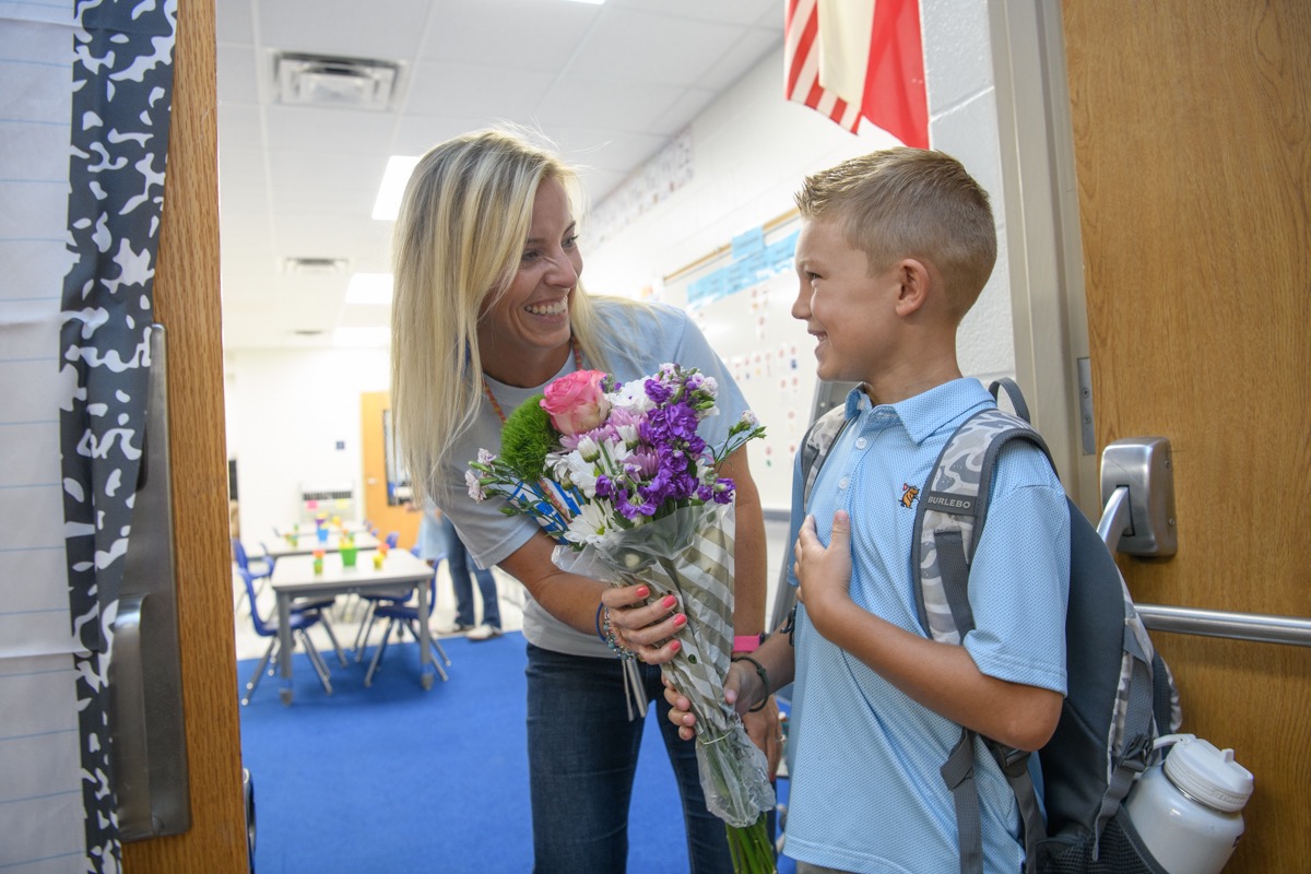 Teacher smiles at a student giving her flowers