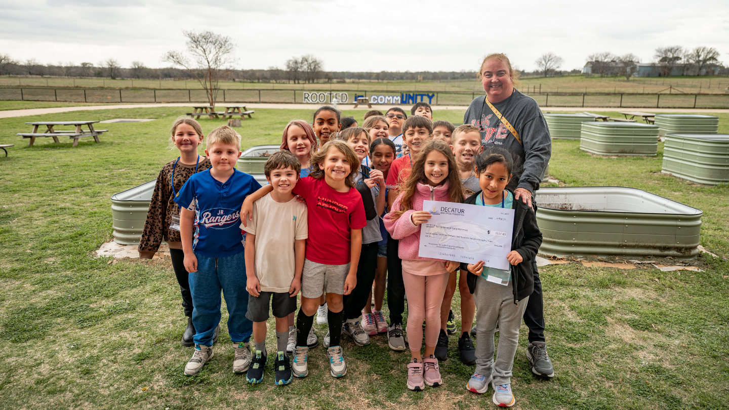 Tammy Rainey and her students pose for a photo tie a giant great check from the Decatur Education Foundation to help fund outdoor learning efforts at Young