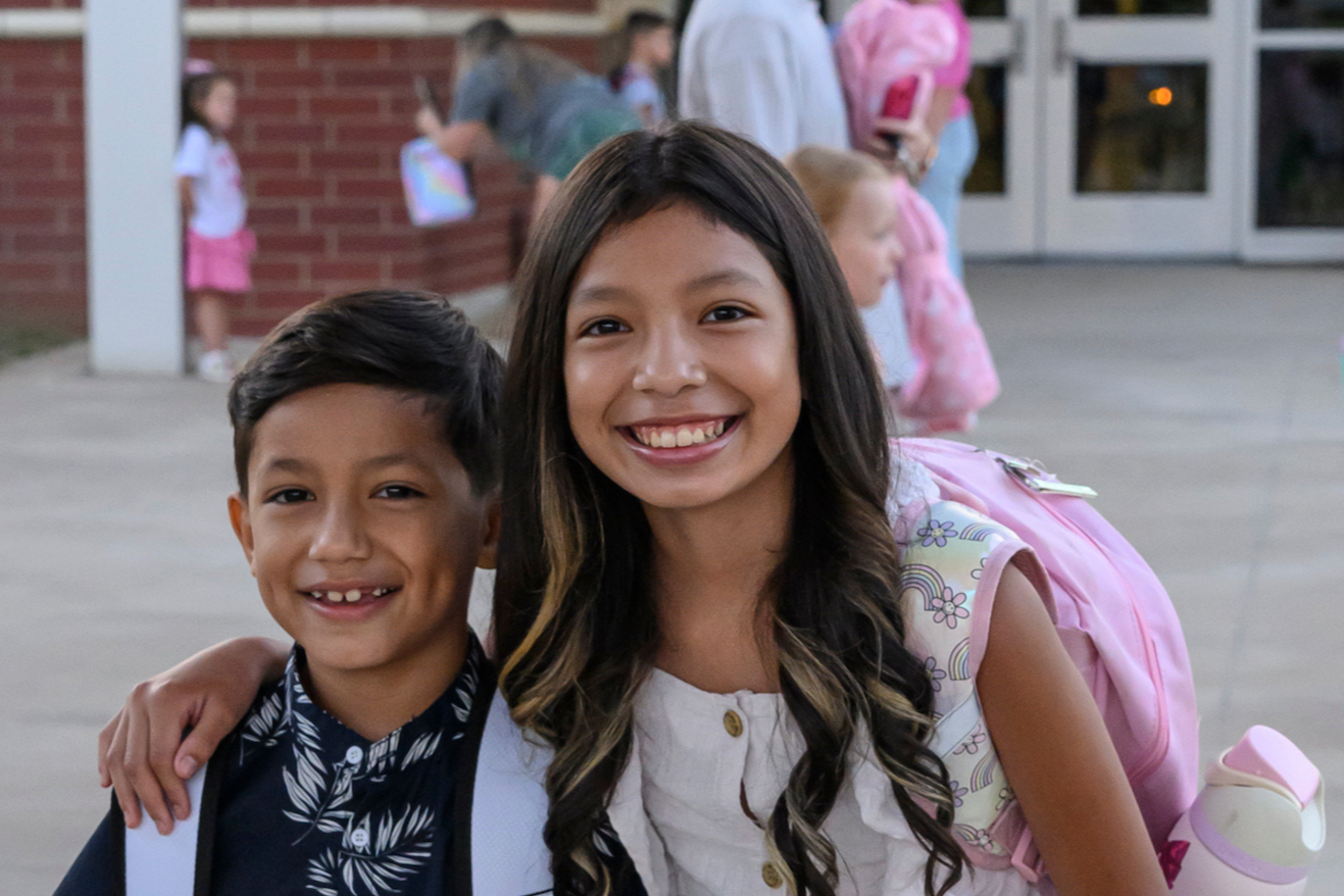 Photo of students wearing backpacks smiling for the camera 