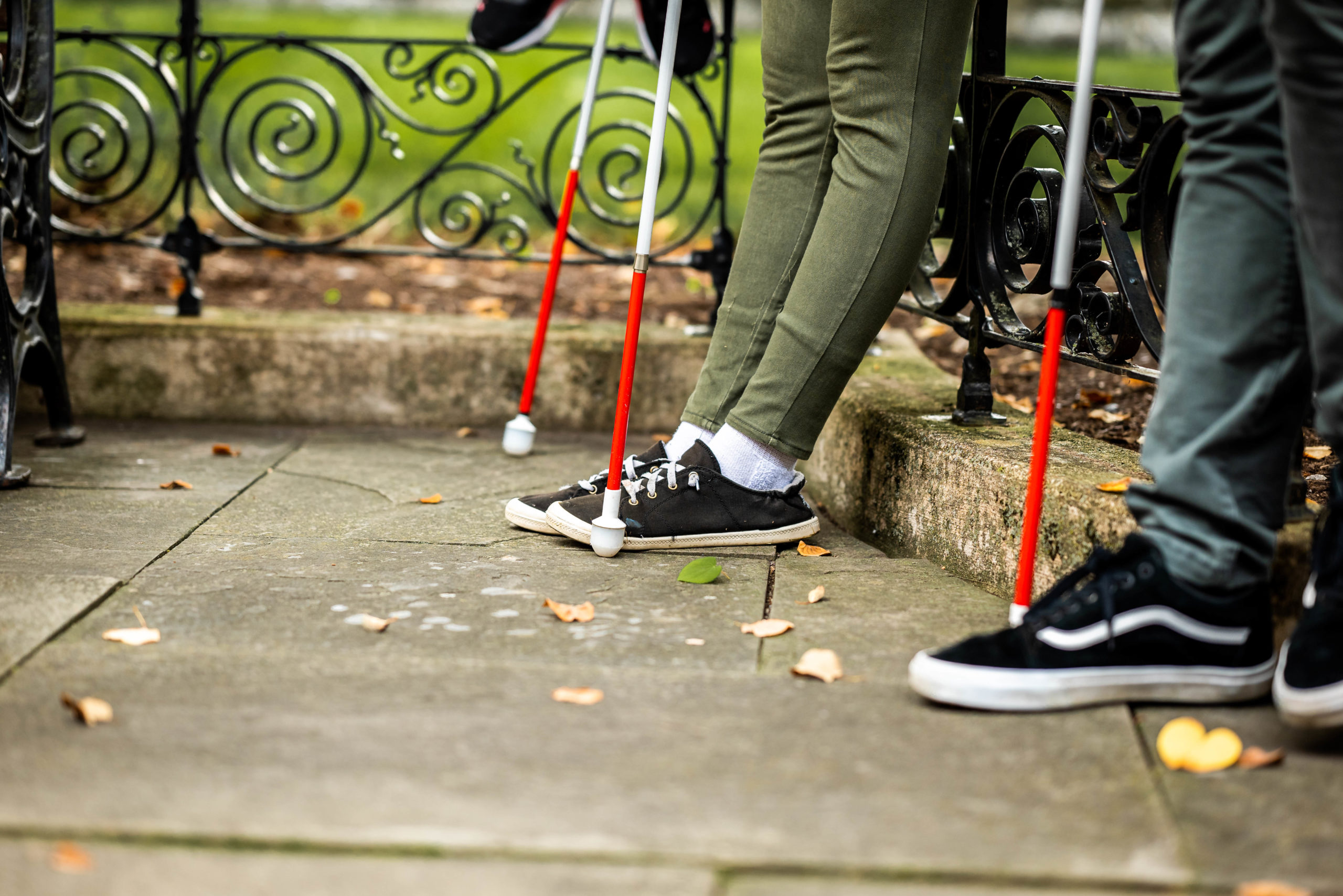 An artistic photo of two people's legs with white canes next to them