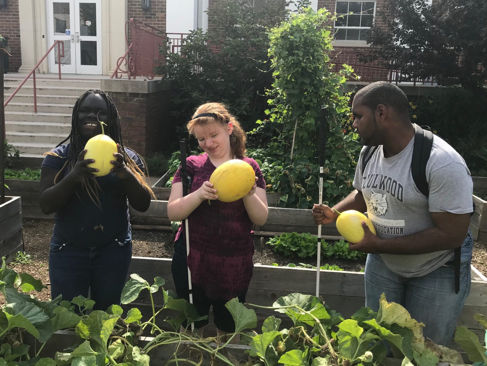 3 students in the garden, each holding a melon