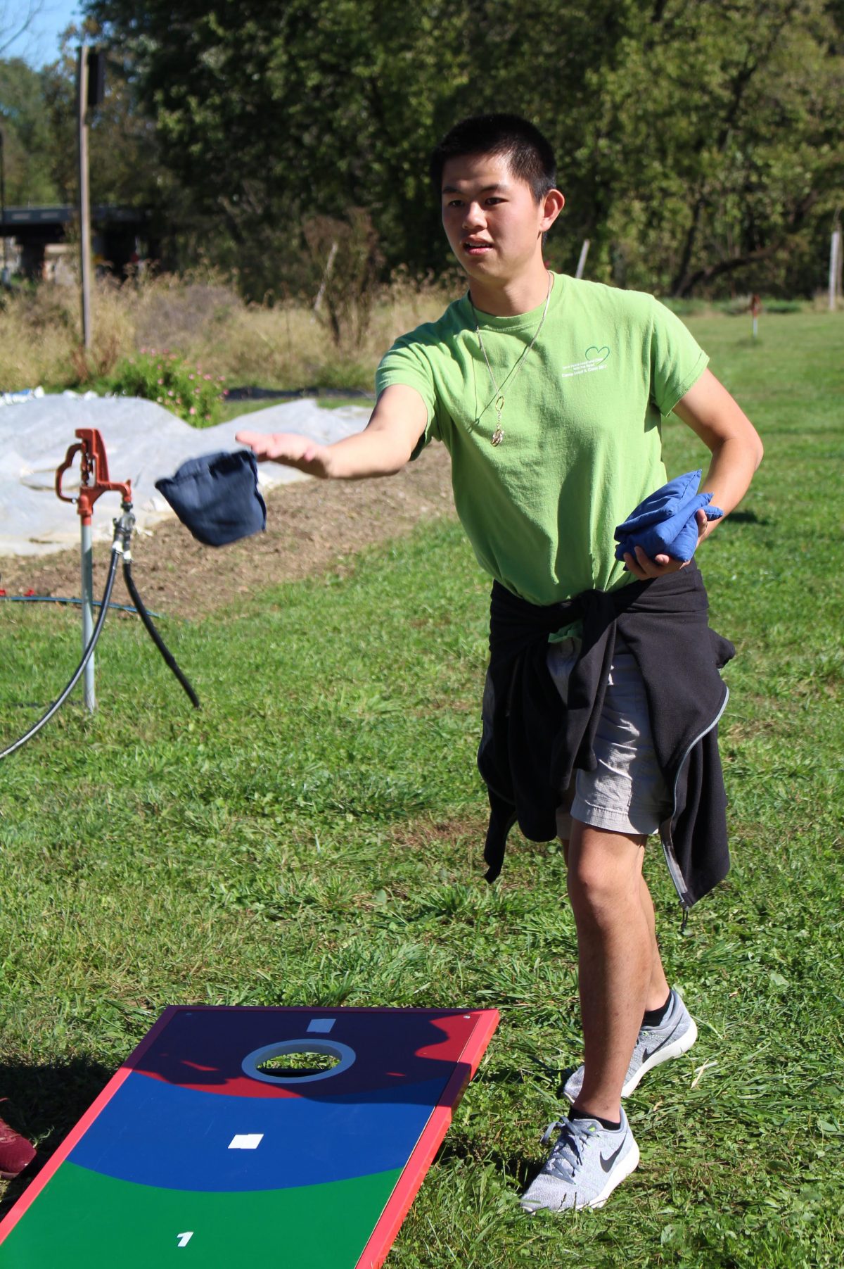 A student tossing a beanbag for a game outside