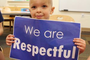 A young student holding a sign reading "We are respectful"