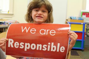 A student holding a sign reading "We are responsible"