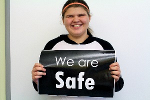 A student holding a sign reading "We are safe"