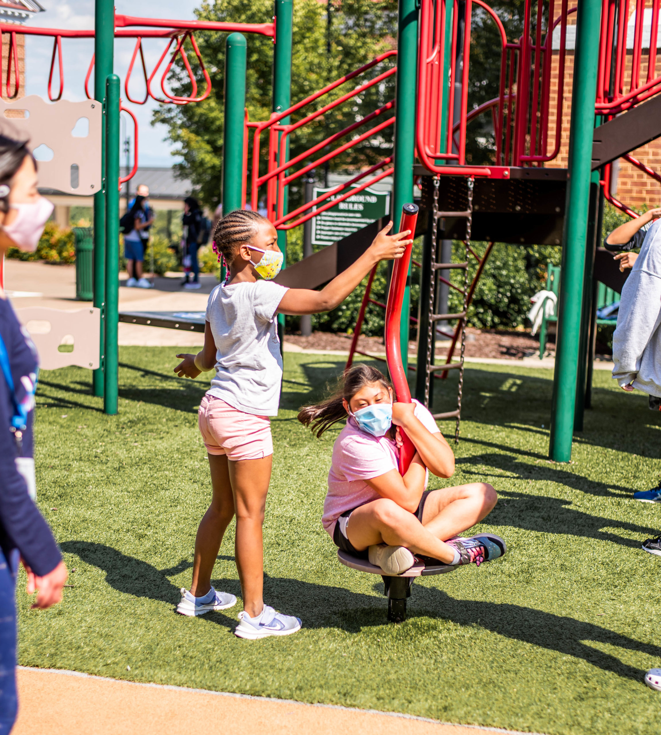 2 students playing around playground equipment during an ice cream social event