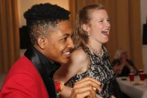 2 students in formal wear smiling at something off screen