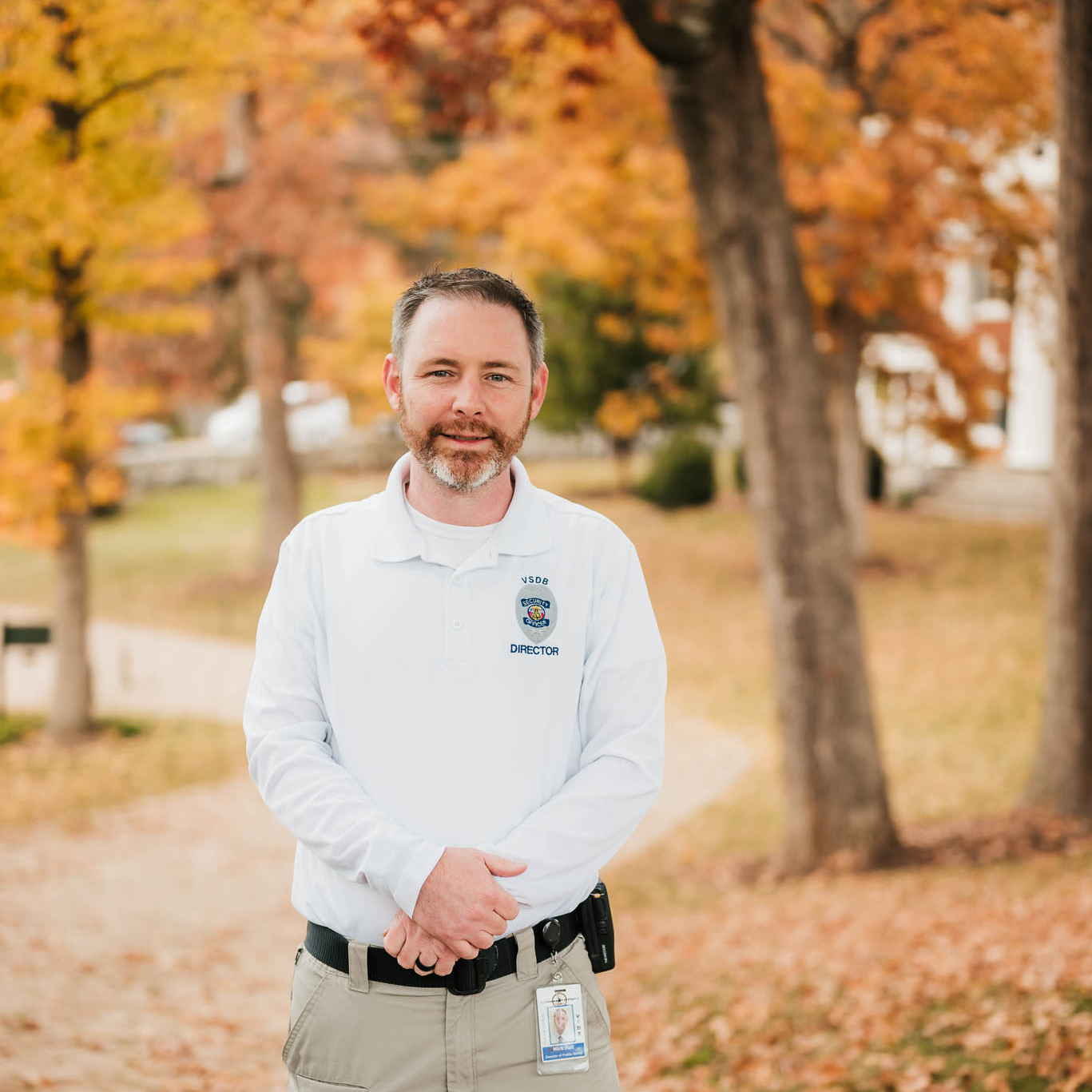 Nick Hall with his hands clasped in front of him outside with trees 