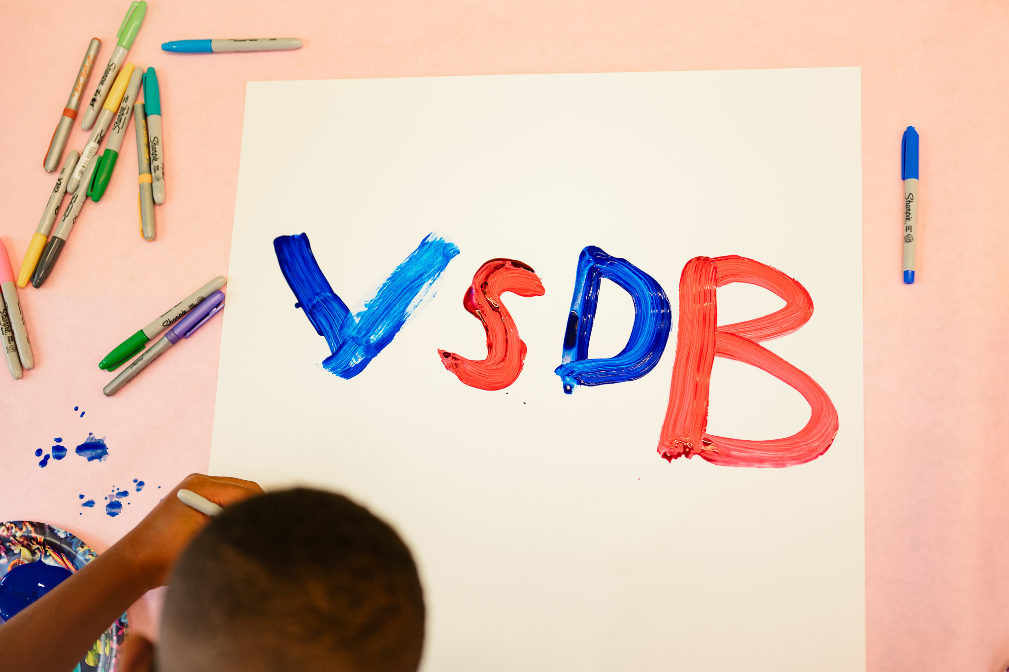 A student draws a VSDB poster in red and blue.