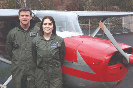 2 STUDENTS STANDING IN FRONT OF PLANE