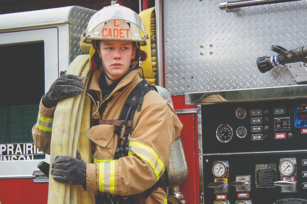 Student in turnouts holding fire hose