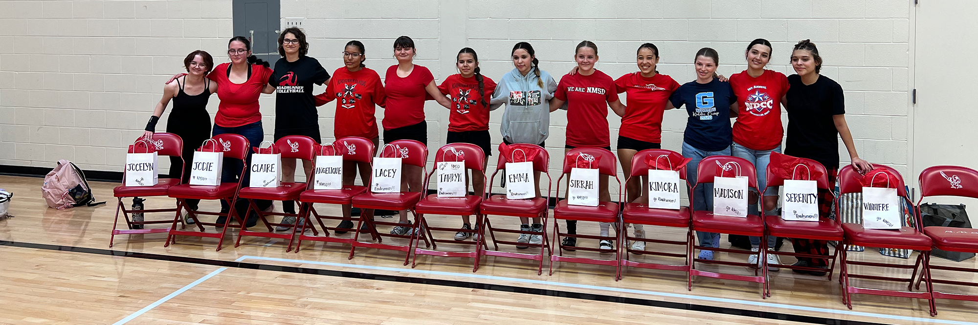 23-24 Girls Varsity Basketball team standing by chairs