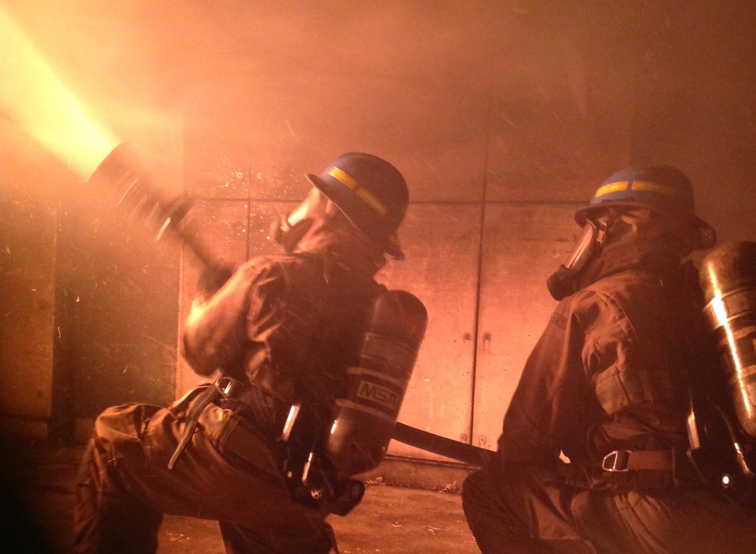 Two fire students using water hose to extinguish a fire