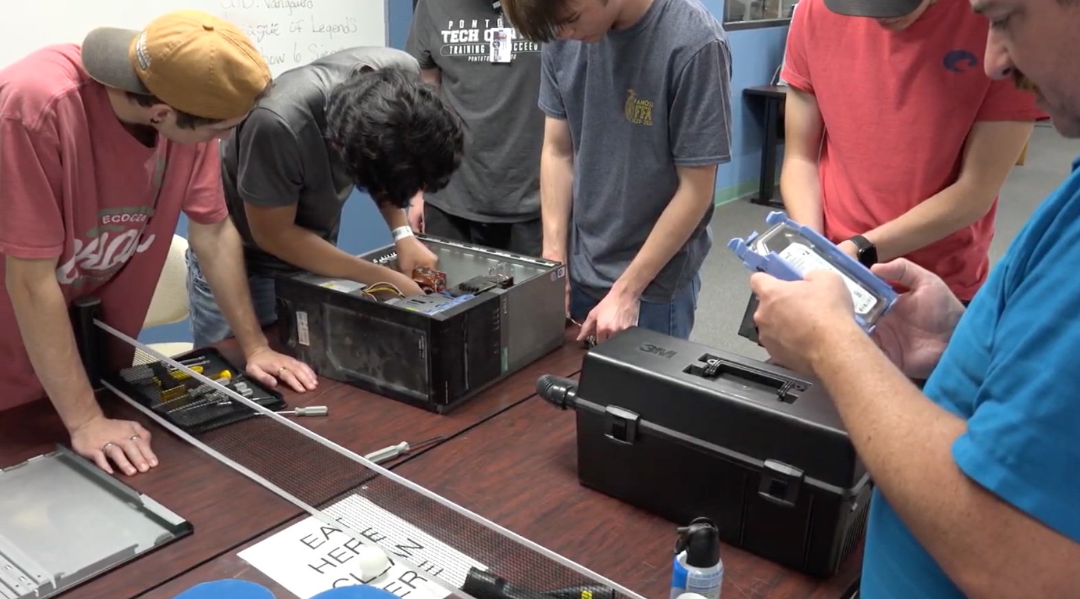 Several students working on the inside of a computer.