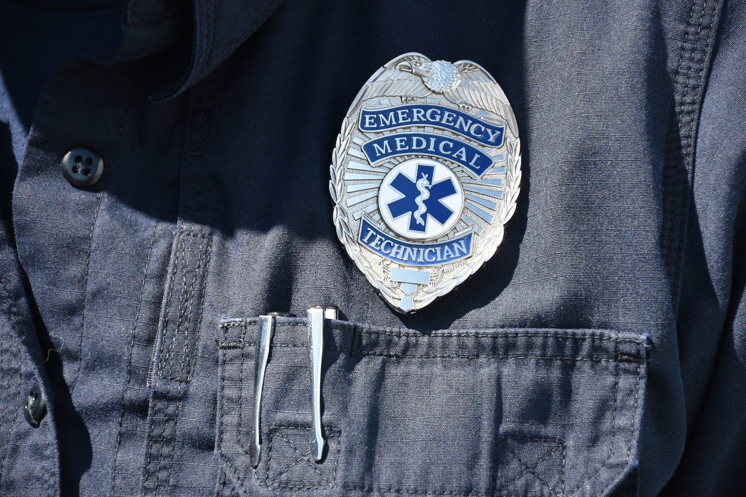 EMT badge pined to a dark blue uniform shirt