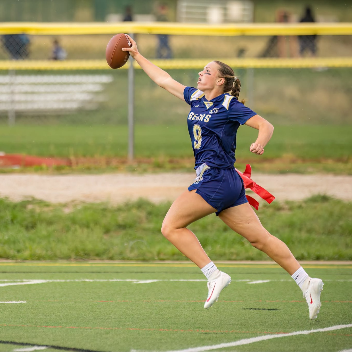A female student reaches the goal line with a football during a flag football game