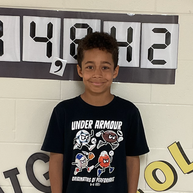 Jay - West Elementary Student standing in front of a bulletin board that reads 14,842