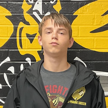 Mac wearing a grey t-shirt with red writing that says Fight and a black jacket standing in front of the MP hawk wall decal