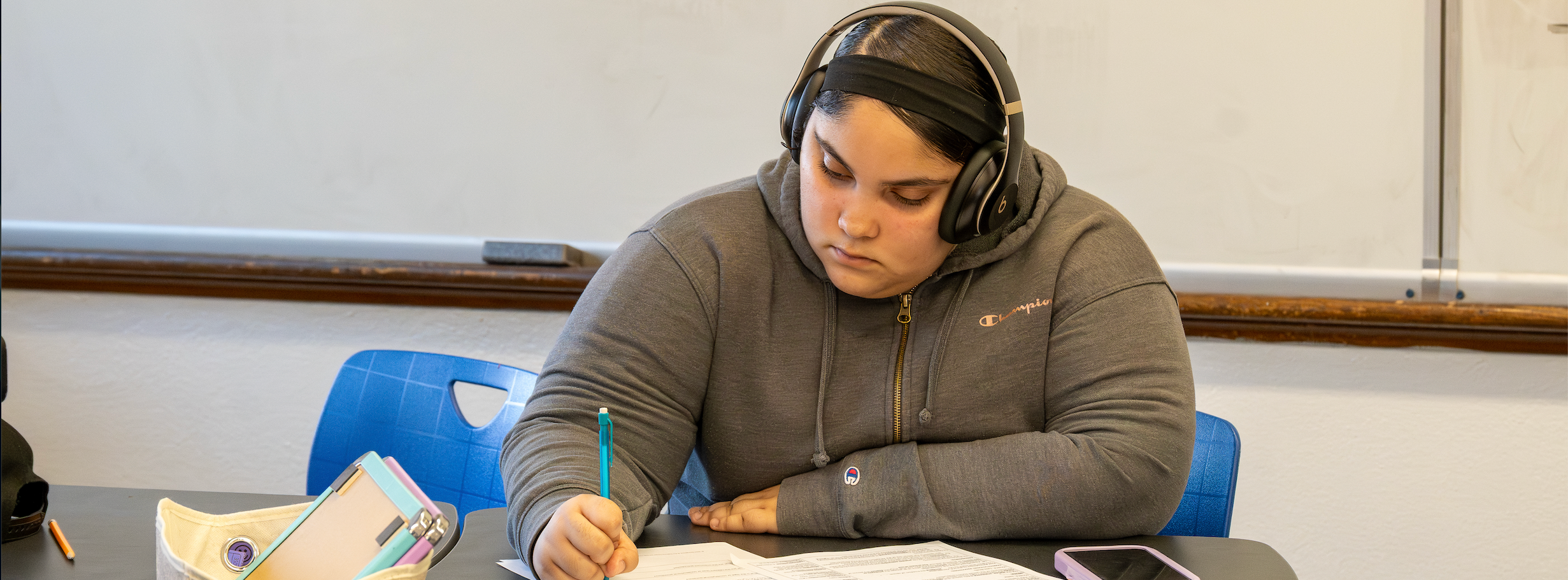 A student works diligently with headphones on