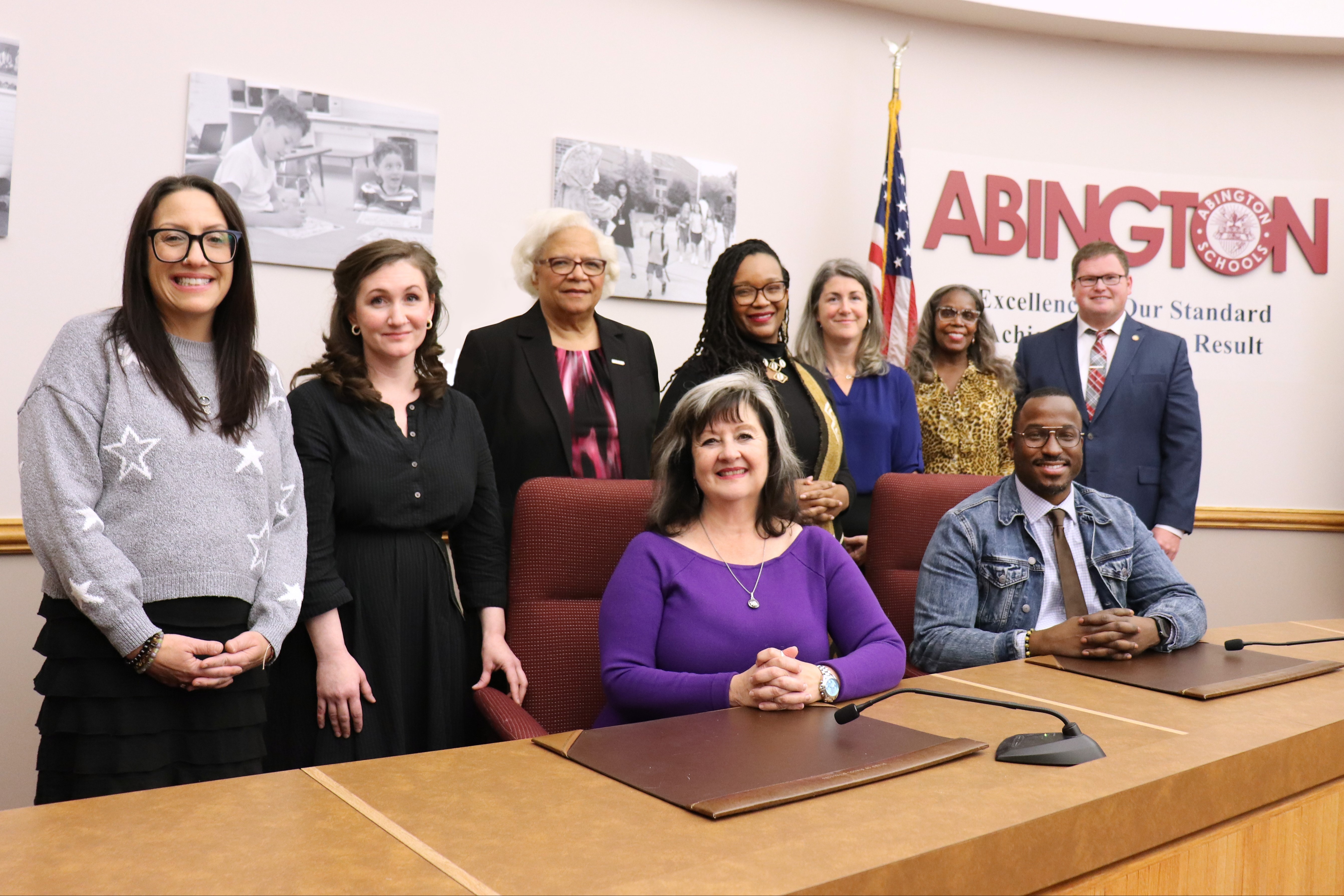 9 school board directors standing and sitting around a table