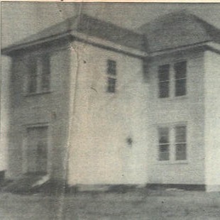 A black-and-white photo of a white two-story building.