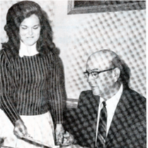 Black-and-white newspaper clipping of a woman in a striped dress handing papers to a seated older man in a suit, with the caption 'COPPELL EDUCATOR — School superintendent W.W. Pinkerton.'