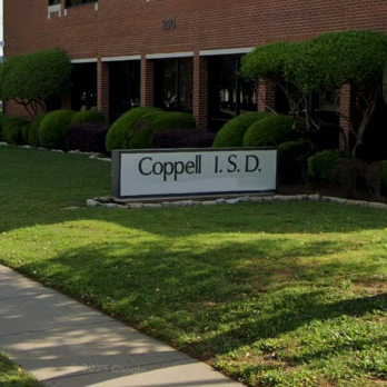 A sign that reads Coppell ISD infront of a building and trees.