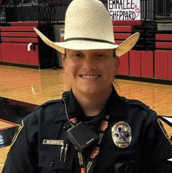 Officer Gomez smiling for the picture with a cowboy hat on the arena floor.