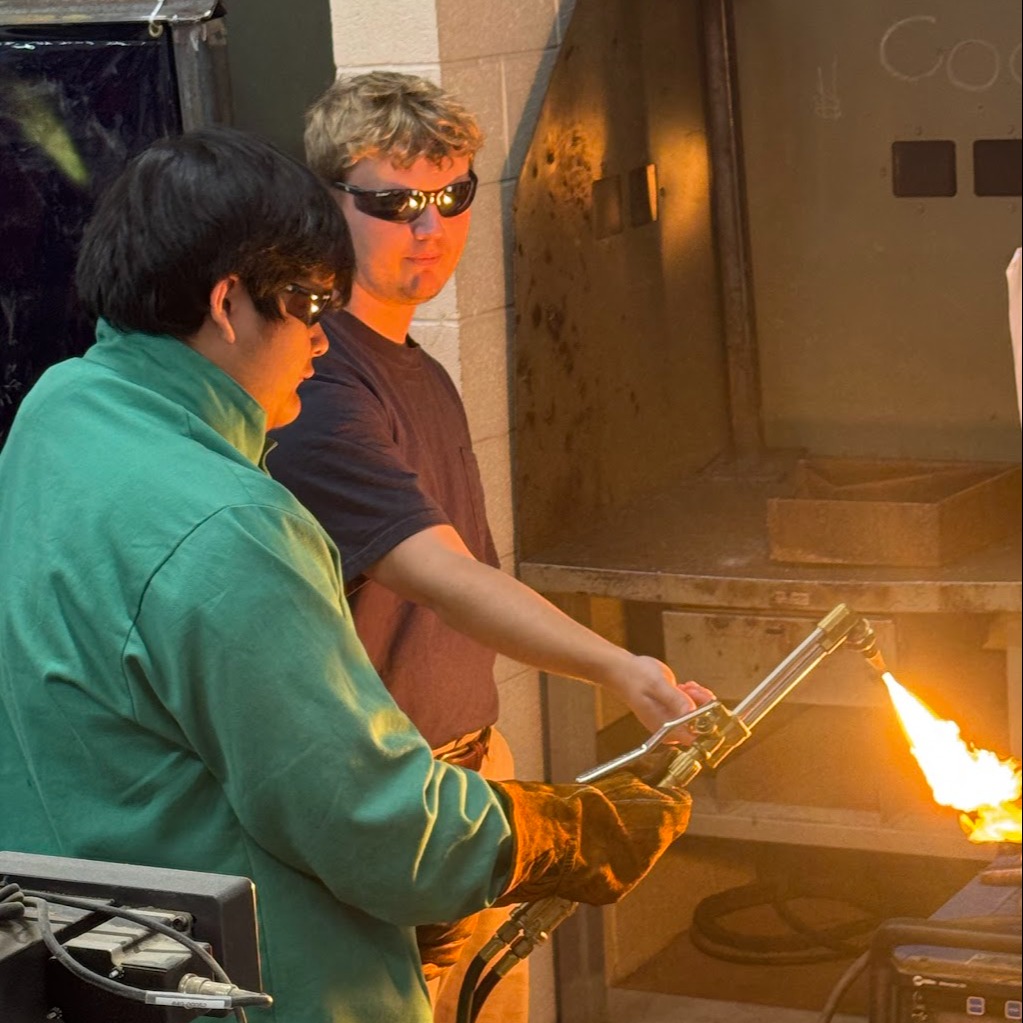 Advanced Manufacturing student using a torch cutter with the assistance of the teacher